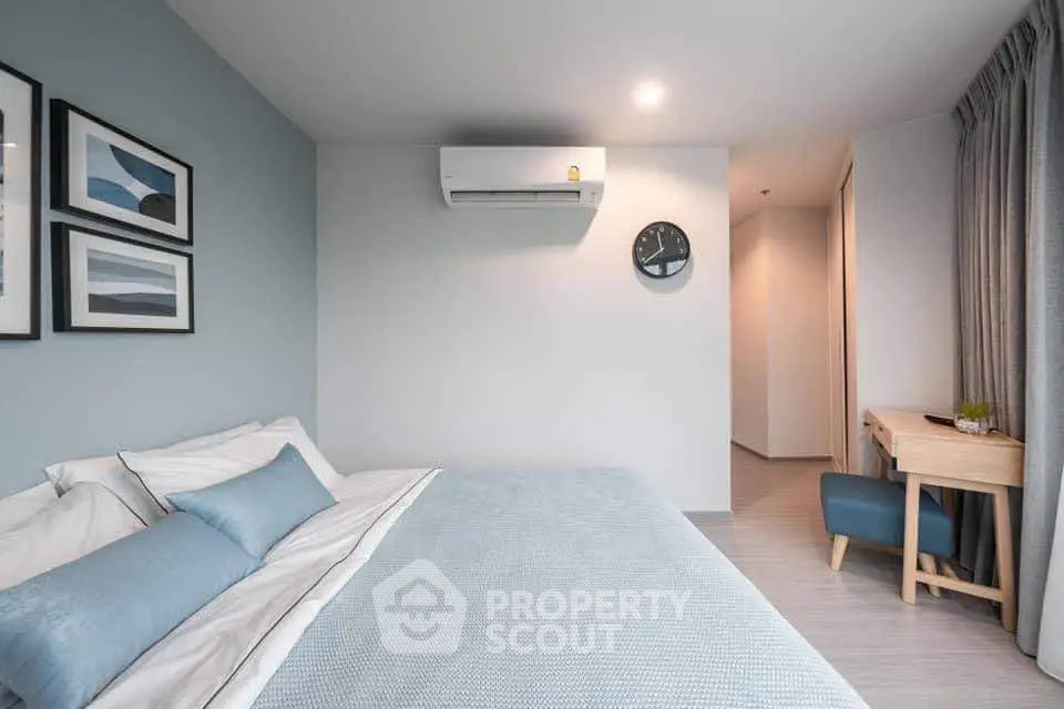 Modern bedroom with stylish decor and air conditioning, featuring a cozy workspace and elegant wall art.