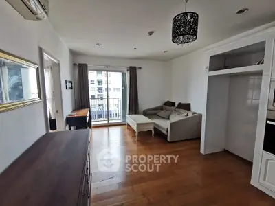 Spacious living room with wooden flooring and balcony access in modern apartment.