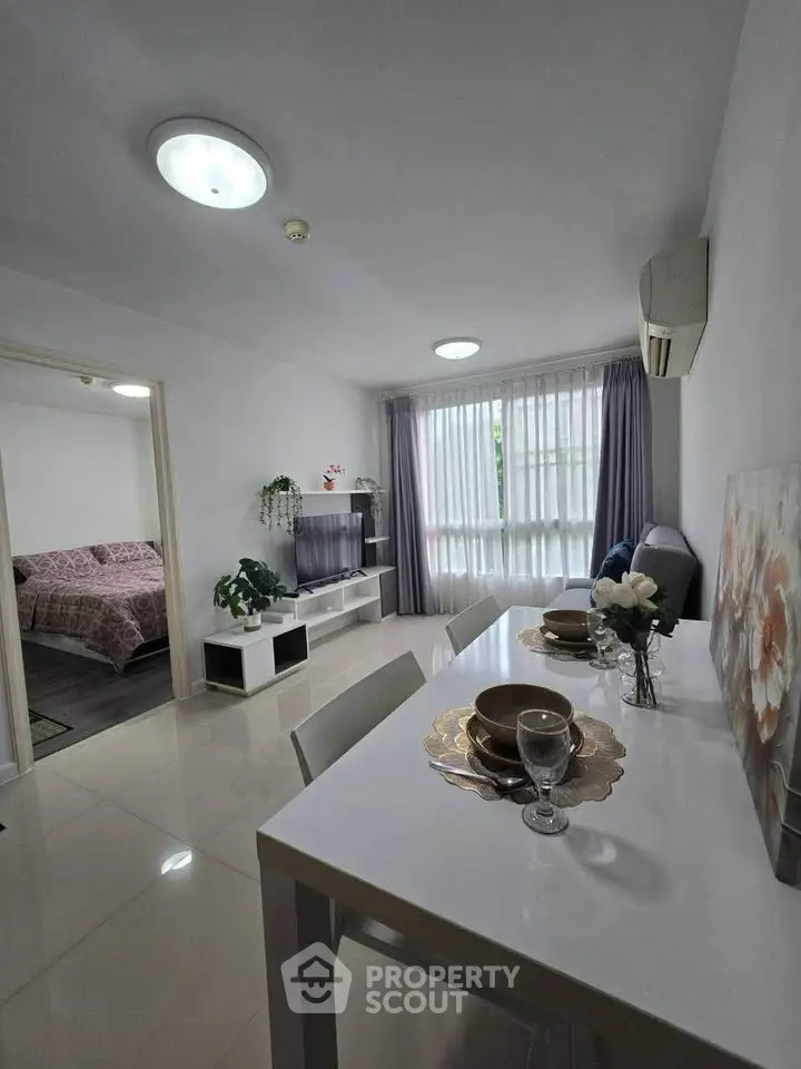 Modern living room with dining area and bedroom view, featuring sleek furniture and elegant decor.