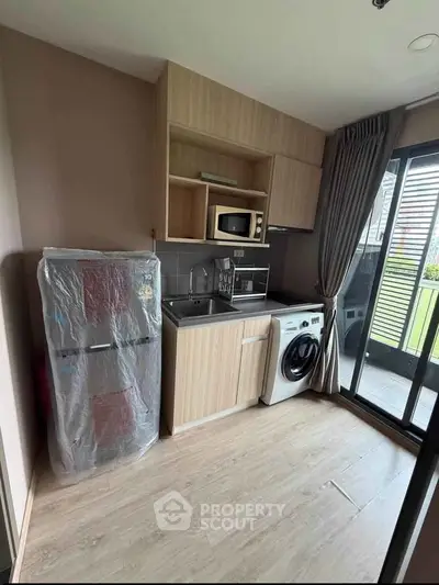 Modern compact kitchen with appliances and balcony access in stylish apartment.