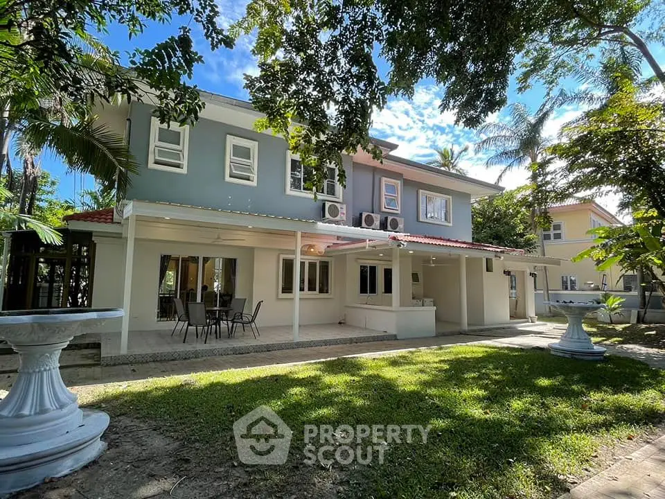 Charming two-story home with spacious backyard and outdoor seating, surrounded by lush greenery.