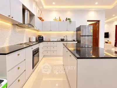 Modern kitchen with sleek cabinetry, black countertops, and stainless steel appliances in a bright, spacious layout.