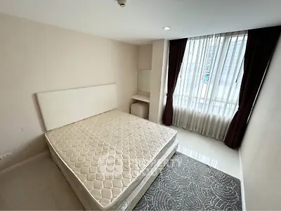 Spacious bedroom with large window and natural light in modern apartment.