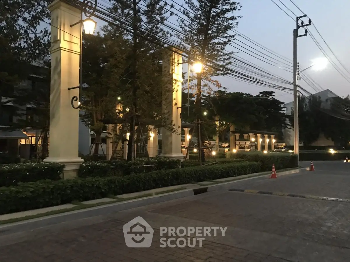 Elegant residential entrance with warm lighting and lush greenery at dusk.
