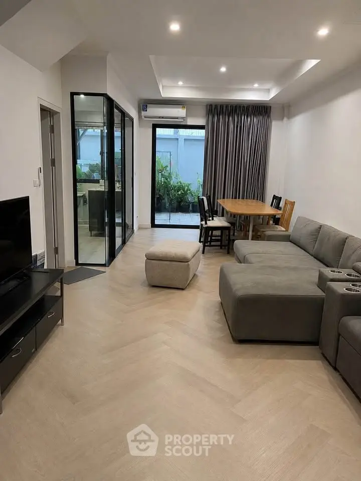 Spacious modern living room with stylish furniture and garden view, perfect for family gatherings.