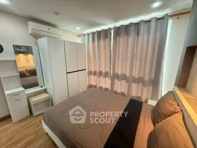 Cozy bedroom with modern furnishings and ample natural light through large windows.