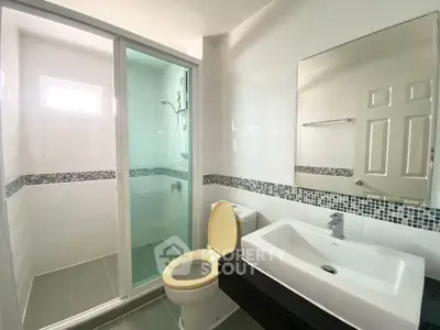 Modern bathroom with glass shower and sleek fixtures in a bright, tiled space.