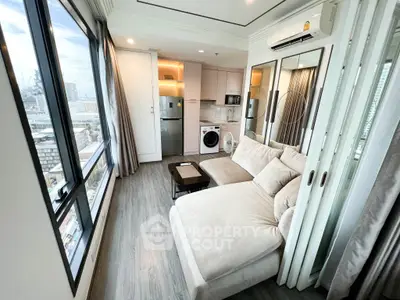 Modern living room with city view, featuring cozy sofa, washing machine, and sleek kitchen appliances.
