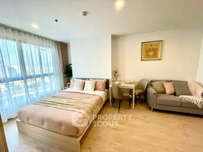 Modern studio apartment with cozy bed, stylish sofa, and dining area, featuring large windows and elegant decor.
