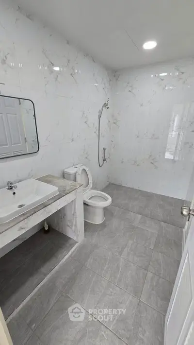Spacious modern bathroom with elegant marble tiles and sleek fixtures.