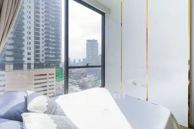 Modern bedroom with city view, large window, and stylish decor in high-rise apartment.