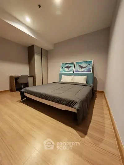 Spacious bedroom with modern decor and wooden flooring in a stylish apartment.