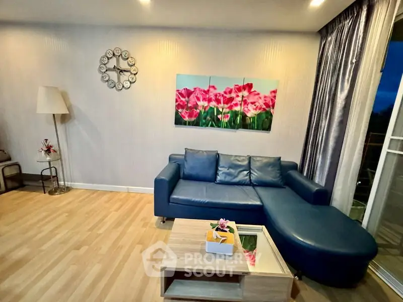 Stylish living room with modern blue sofa and floral artwork, perfect for relaxation.