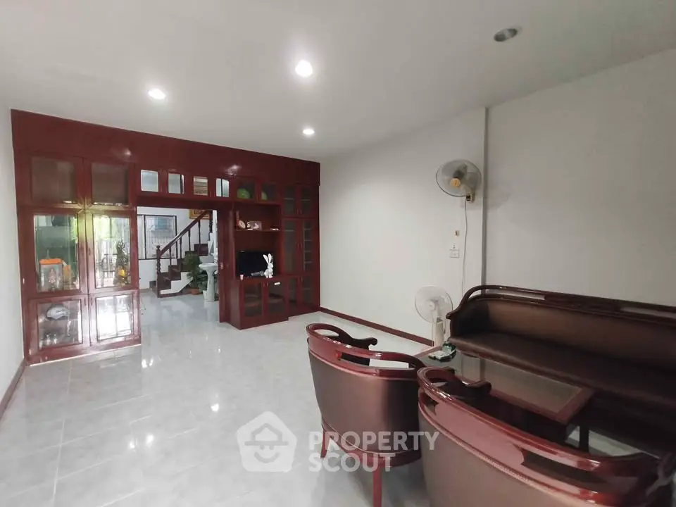 Spacious living room with elegant wooden furniture and bright lighting, perfect for family gatherings.