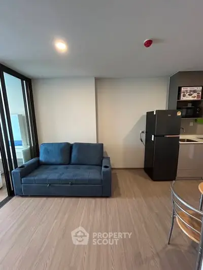Modern living room with blue sofa and kitchenette in open layout apartment.