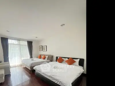 Spacious bedroom with two beds and large window, perfect for comfort and relaxation.