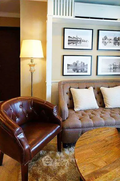 Elegant living room with leather chair, plush sofa, and framed art, perfect for cozy relaxation.