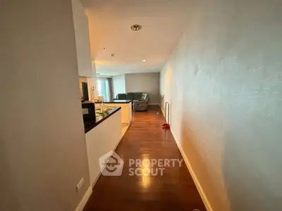 Spacious hallway leading to a cozy living room with modern decor and wooden flooring.