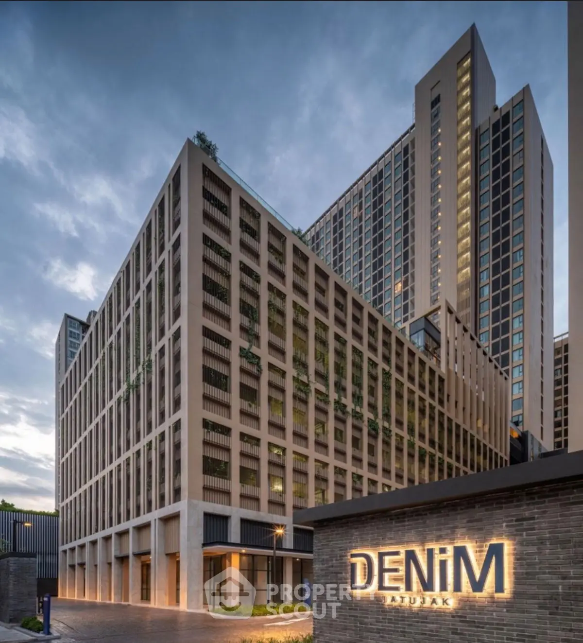 Modern high-rise building with sleek architecture and illuminated signage at dusk.