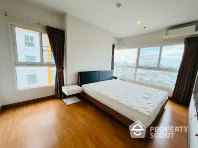 Spacious bedroom with large windows offering stunning city views and natural light.