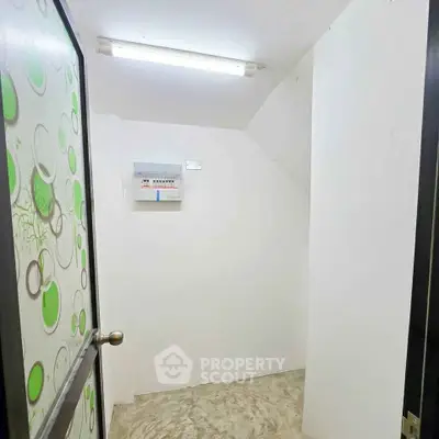 Compact storage room with unique door design and overhead lighting