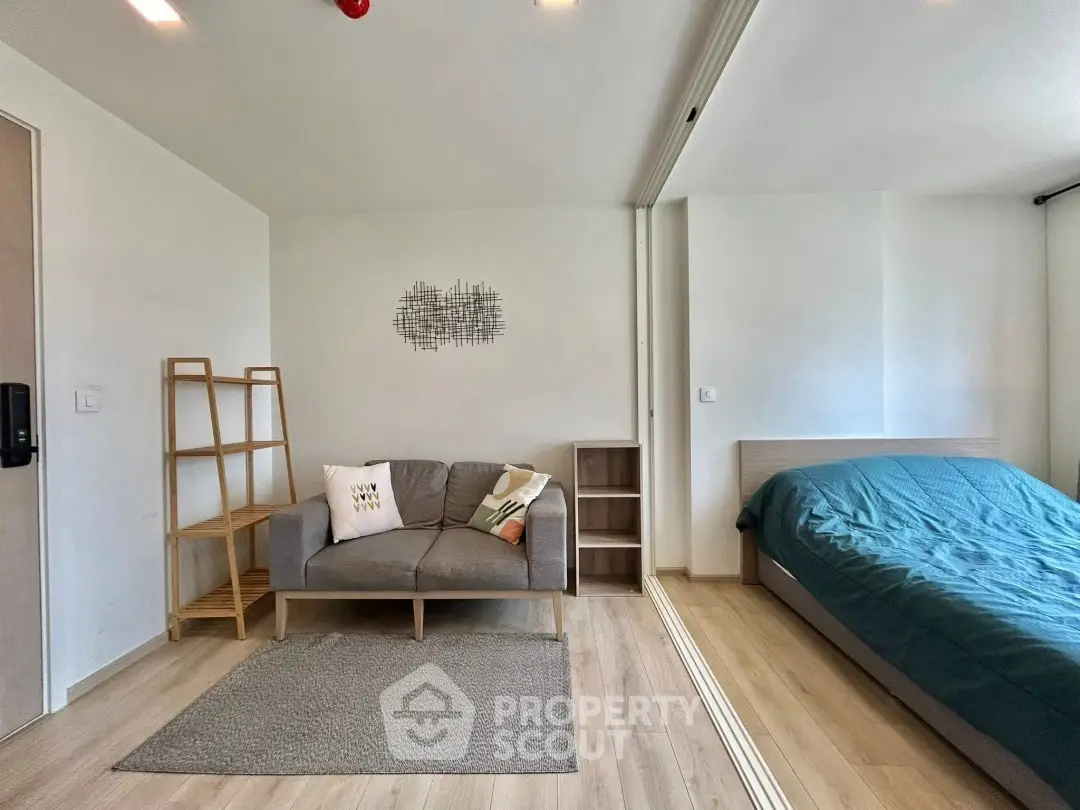 Modern studio apartment with cozy living area and bed, featuring minimalist decor and wooden flooring.