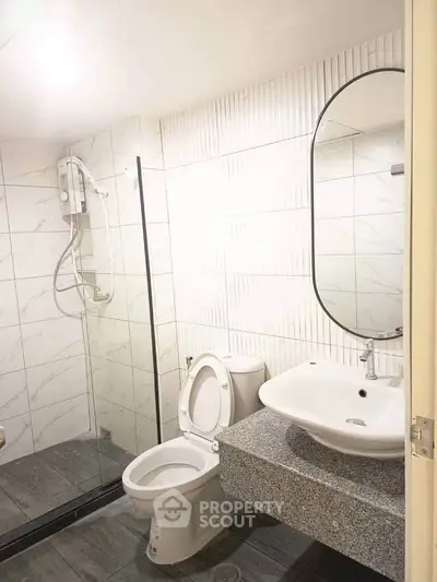 Modern bathroom with sleek fixtures and glass shower enclosure in a stylish apartment.