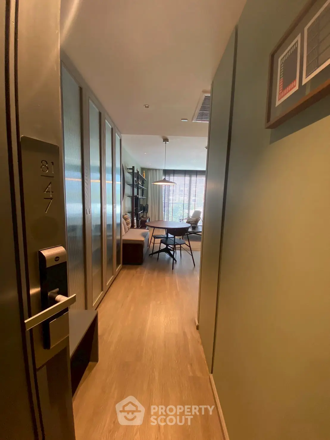 Modern apartment entrance leading to a stylish living room with wooden flooring and contemporary decor.