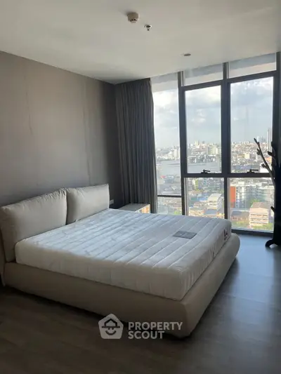 Modern bedroom with large windows offering stunning city views and natural light.