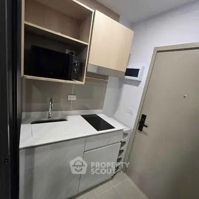 Compact modern kitchen with sleek cabinetry and built-in appliances in a cozy apartment.