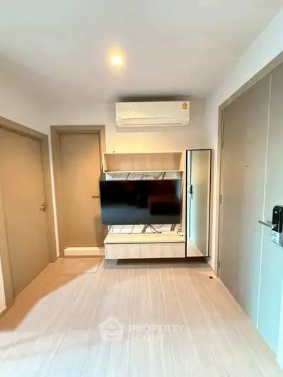 Modern living room with wall-mounted TV and air conditioning unit, featuring sleek wooden flooring.