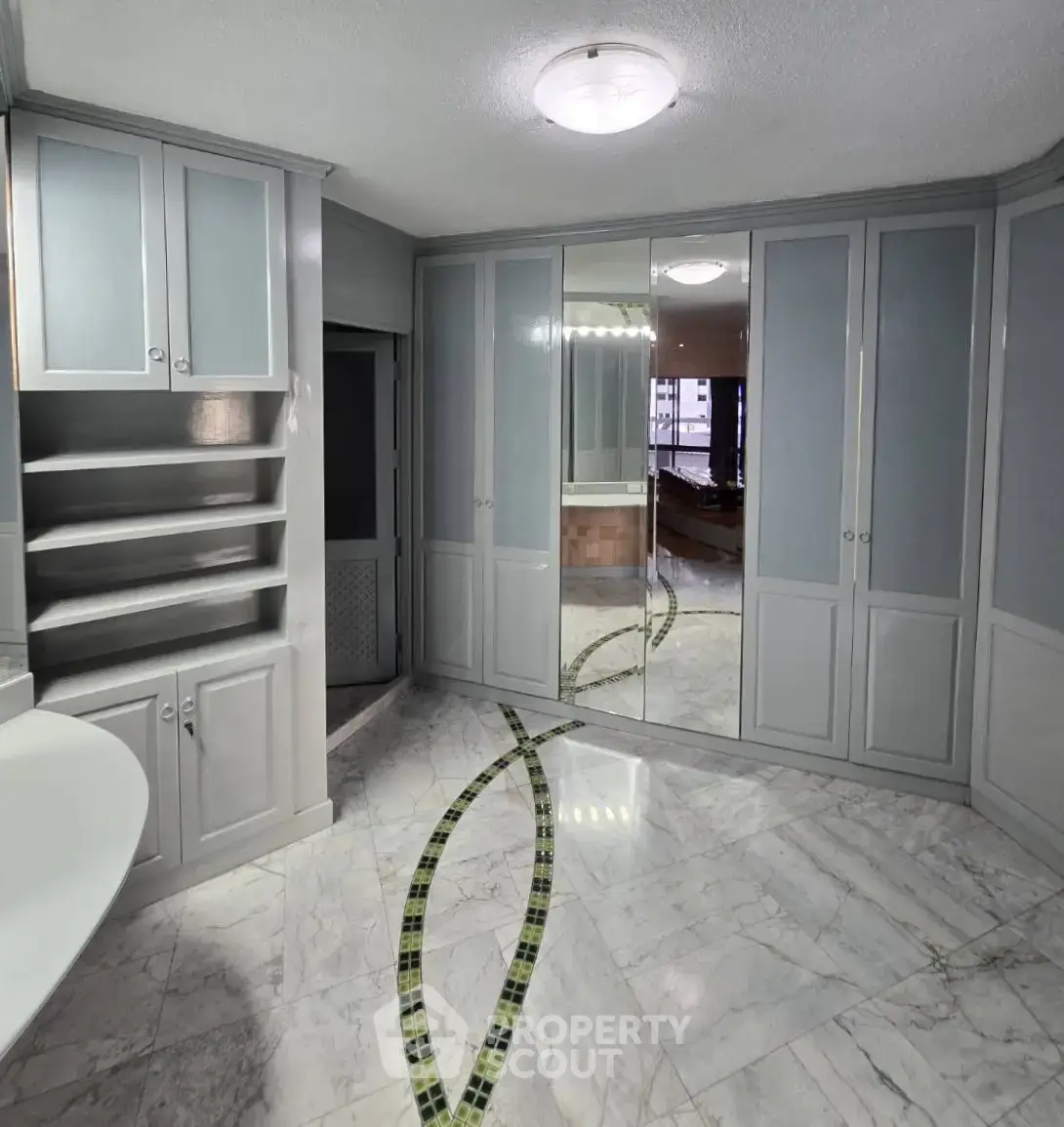 Spacious bathroom with elegant marble flooring and ample storage cabinets.