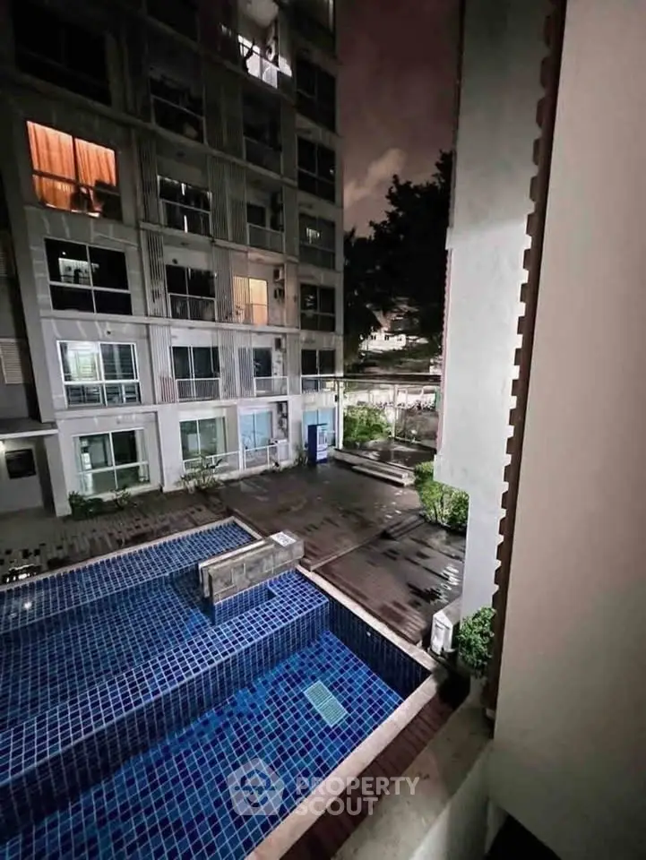 Modern apartment building with illuminated windows and a stylish outdoor pool at night.