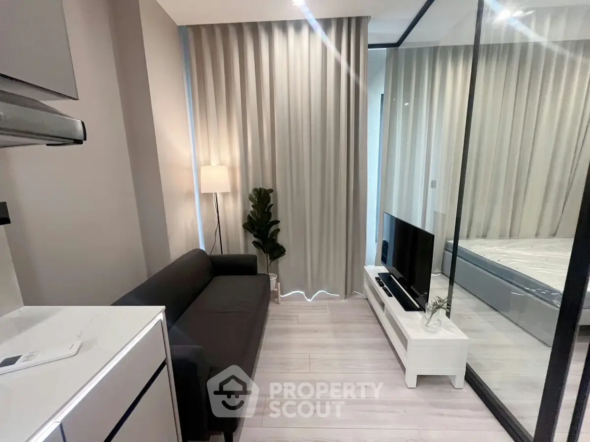 Modern compact living room with sleek design and glass partition, featuring a cozy sofa and stylish decor.