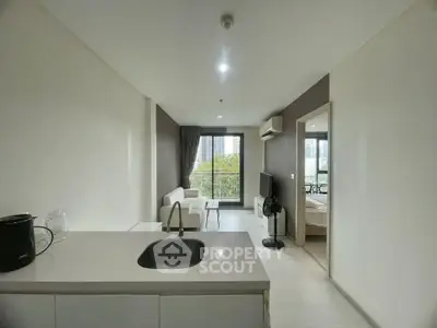 Modern open-plan living room with kitchen, featuring large windows and city view.