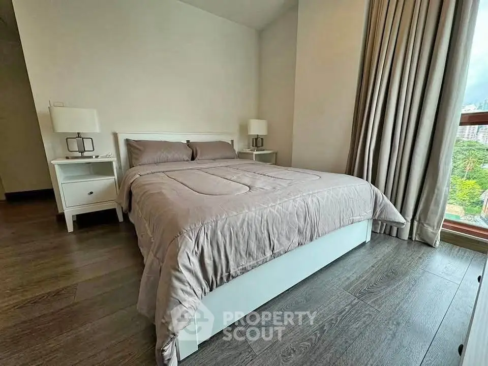 Cozy bedroom with modern decor and large window offering natural light.
