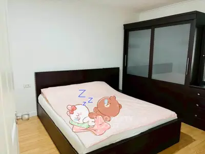 Cozy bedroom with dark wood furniture and playful cartoon bedding, perfect for a restful retreat.