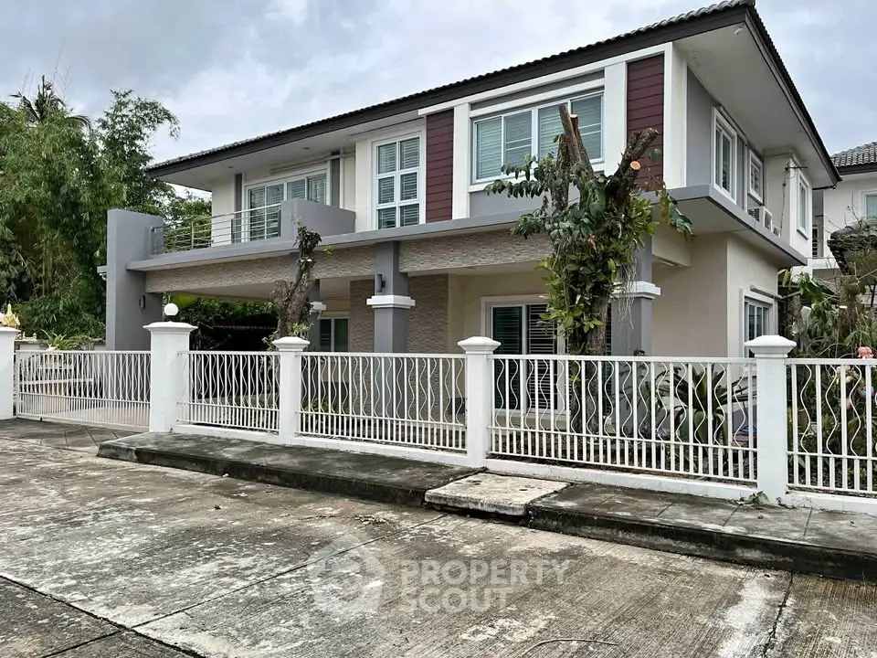 Modern two-story house with white fence and lush greenery
