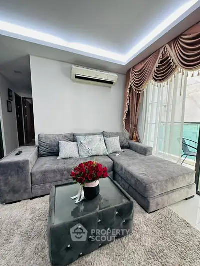 Luxurious living room with plush gray sectional sofa, elegant drapes, and modern decor in a stylish apartment.