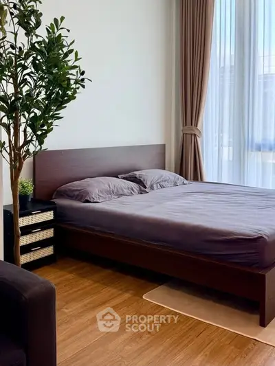 Modern bedroom with wooden flooring, large window, and elegant curtains.