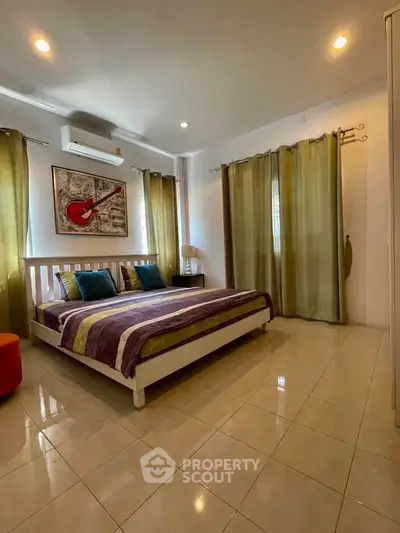 Spacious bedroom with modern decor and natural light, featuring a comfortable bed and stylish curtains.