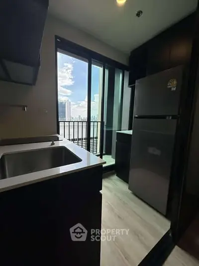 Modern kitchen with balcony view, featuring sleek appliances and ample natural light.