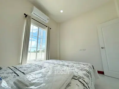 Bright bedroom with air conditioning and large window offering natural light