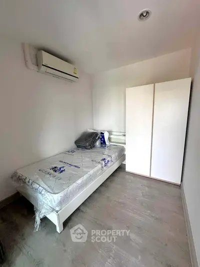 Cozy minimalist bedroom with air conditioning and wardrobe, perfect for a comfortable living space.