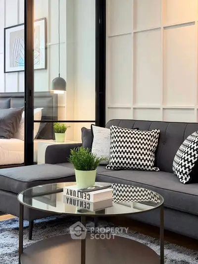 Modern living room with stylish decor and glass partition leading to bedroom.