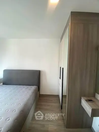 Modern bedroom with sleek wooden wardrobe and comfortable bed in a minimalist design.