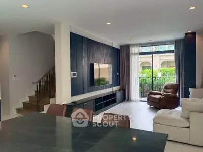 Modern living room with sleek design, large TV, and comfortable seating overlooking a garden view.