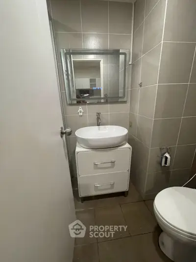 Compact modern bathroom with sleek fixtures and neutral tiles, featuring a stylish vanity and mirror.