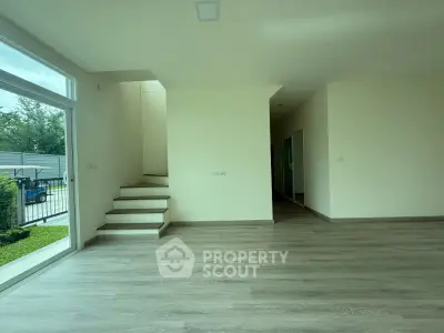Spacious modern living room with large windows and staircase, perfect for natural light lovers.