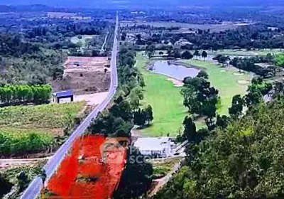 Scenic aerial view of expansive land plot near lush golf course and countryside road.
